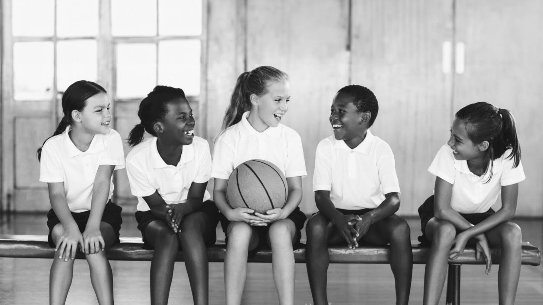 Kinderen zittend op de bank met een basketbal.